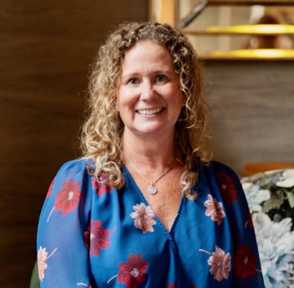 Liz, owner of Wild West Adventures, smiling in a blue floral top