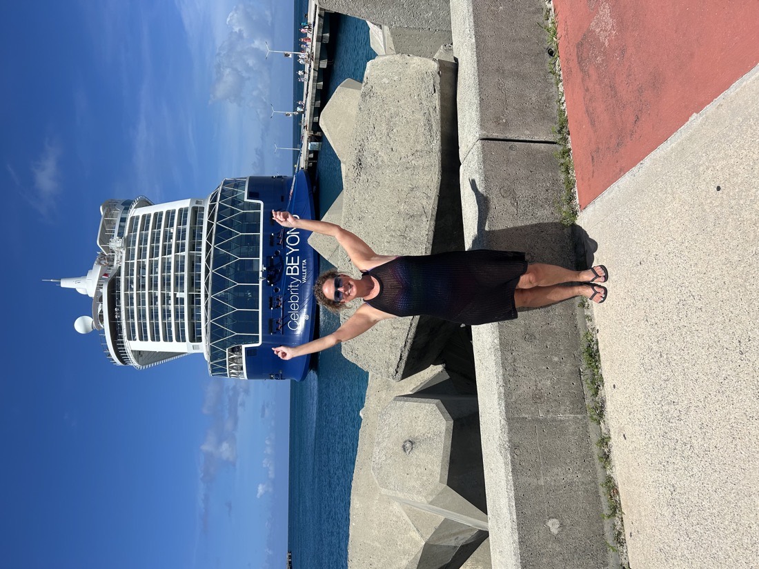 Liz with her arms raised in front of the Celebrity Beyond at the pier